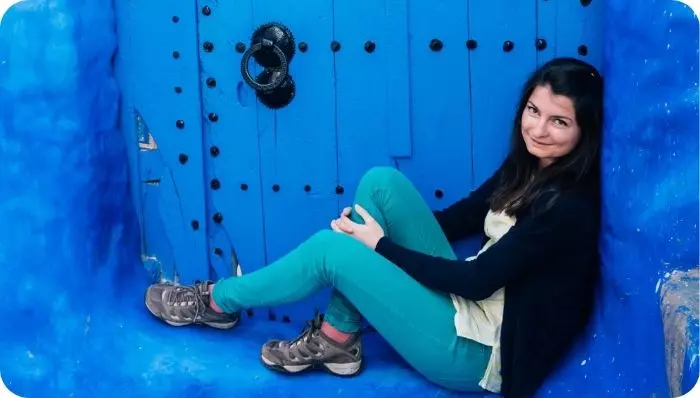 Turista posando en una puerta azul en Chefchaouen